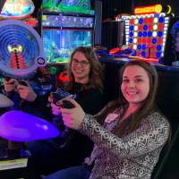 Two alumni smiling before playing arcade game